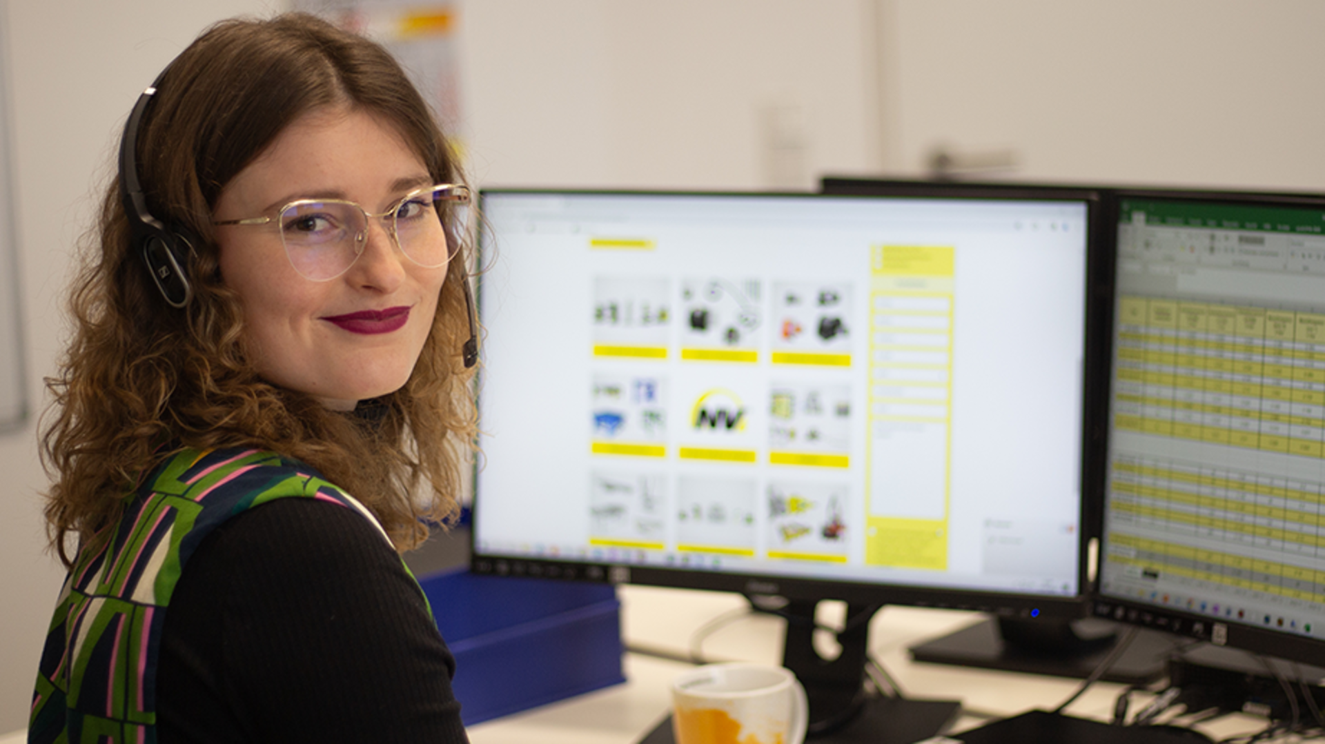 Frau sitzt am PC mit Telefon-Headset