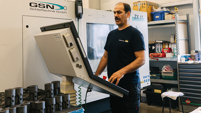 Mitarbeiter aus Produktion steht an Produktionsmaschine im Bereich Schleifen