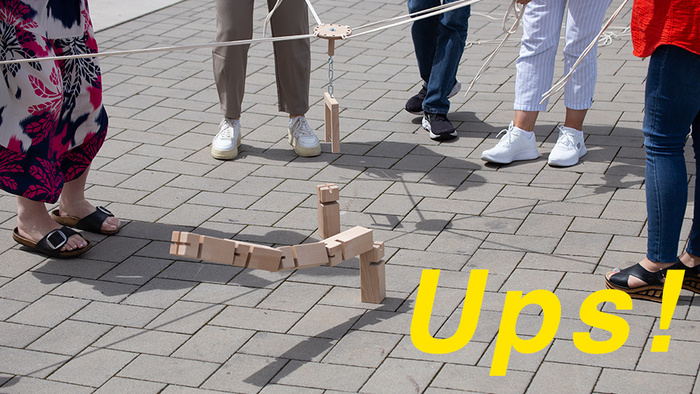 Bild vom Sommerfest, auf dem ein Jenga-Turm umfällt mit Aufschrift Upps